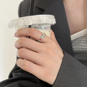 Hand wearing a silver S925 ring with colorful enamel flowers on a glass background