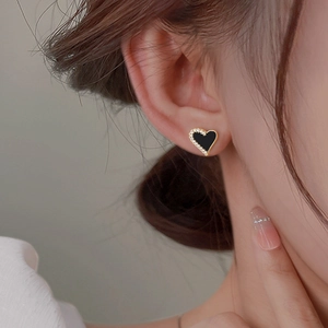 Close-up of black heart earrings with white zircon accents on model's ear