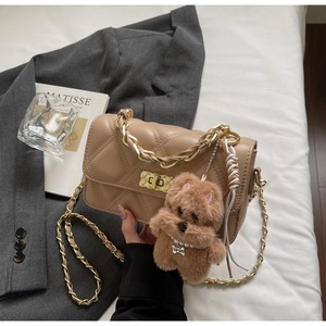 Quilted beige crossbody bag with gold chain strap and cute puppy charm on a soft blazer