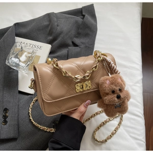 Detail of camel quilted crossbody bag with gold chain strap and cute puppy pendant accessory
