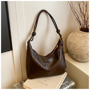 Detail of dark brown leather hobo bag with knotted strap and tassel on a stylish setting
