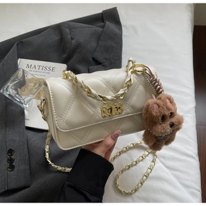 Detail of off-white quilted chain bag with gold twist lock and plush bear pendant