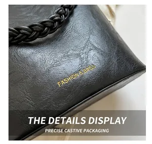 Détail du sac seau en cuir noir vintage avec poignée tressée et lettrage doré chic