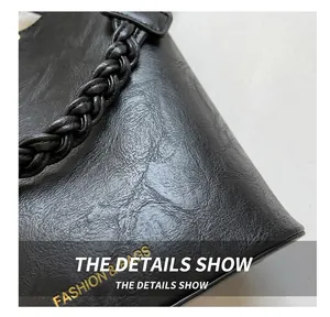 Détail d'un sac à main en cuir noir texturé avec texte doré et bandoulière tressée