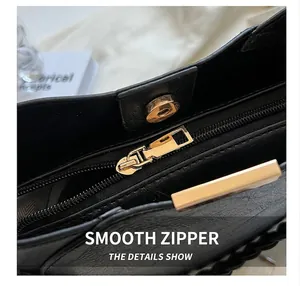 Détail de la fermeture éclair dorée et du fermoir magnétique sur le sac seau noir