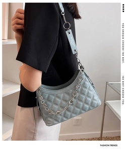 Detail of light blue quilted crossbody bag with decorative silver floral chain and strap