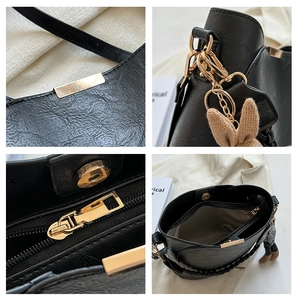 Détail du sac seau en cuir noir avec ferrures dorées et breloque lapin mignonne
