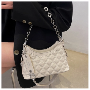 Detail of cream quilted crossbody bag featuring unique gold floral chain and leather strap