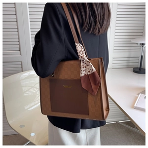 Brown leather tote bag worn by a model in a minimalist room showing its large capacity
