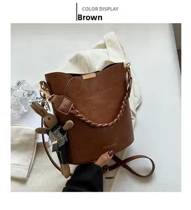 Détail d'un sac seau marron avec poignée tressée et charmant pendentif lapin