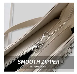 Detailed close-up of the smooth silver zipper and fine stitching on a beige quilted bag
