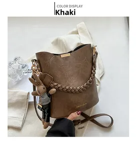 Détail du sac seau kaki avec texture litchi, poignée tissée et pendentif lapin mignon