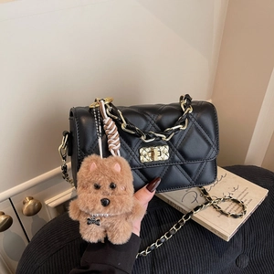 Quilted black crossbody bag with gold chain strap and plush dog charm in urban style