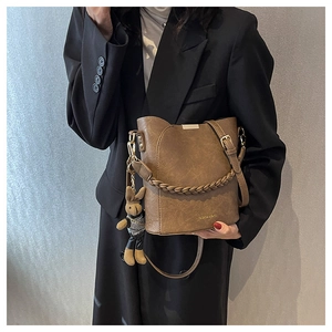 Détail du sac seau marron rétro montrant le cuir PU texturé et la sangle tissée