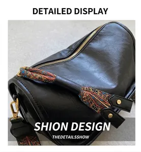 Détail du sac cylindrique noir montrant le grain du cuir et la bandoulière ethnique