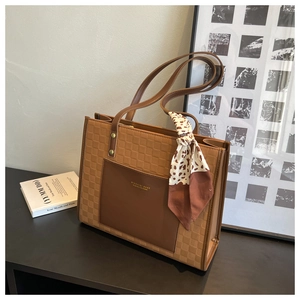 Detailed view of brown checkered tote bag with leather pocket and floral silk scarf decor