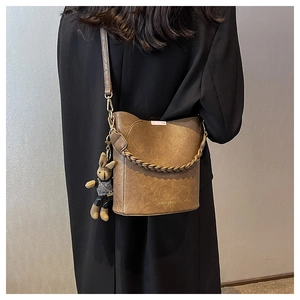 Gros plan sur un sac seau vintage marron avec poignée tressée et charm lapin mignon