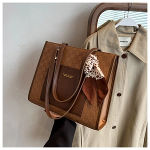 Close-up of vintage brown checkered tote bag with silk scarf on a trench coat background