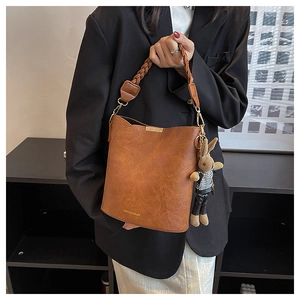 Vue détaillée du sac seau en cuir marron avec anse tressée et breloque lapin mignonne