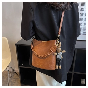 Détail du sac seau vintage en cuir marron avec poignée tressée et breloque lapin