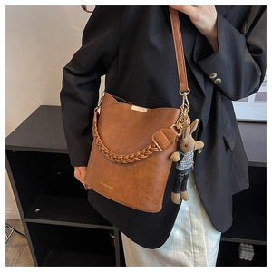 Sac seau en cuir marron avec poignée tressée et breloque lapin porté sur modèle