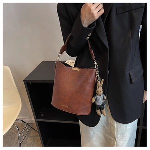 Gros plan du sac seau marron rétro avec poignée tressée et breloque lapin mignonne