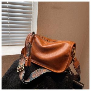 Gros plan sur la texture en cuir synthétique marron et la bandoulière tissée vintage