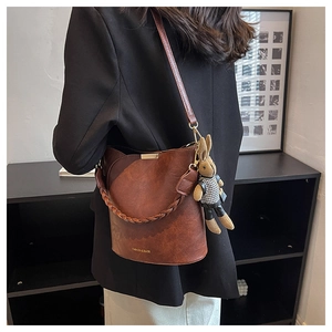 Sac seau vintage marron avec poignée tressée et breloque lapin sur un mannequin