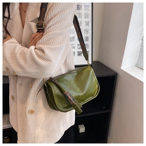 Détail du sac bandoulière vert en cuir avec une large sangle aux motifs bohèmes