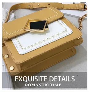 Détail d'un sac bandoulière bicolore avec boucle géométrique dorée et côtés en accordéon