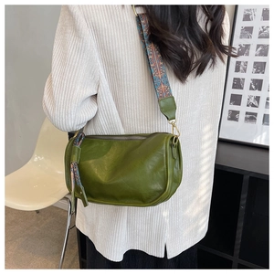 Détail du sac polochon en cuir vert foncé avec une large bandoulière à motif ethnique