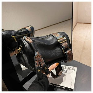 Détail du sac cylindre en cuir noir avec large bandoulière ethnique et fermetures métalliques