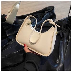 Detailansicht der cremefarbenen Ledertasche mit Goldreißverschlüssen auf Schwarz