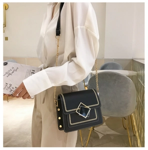 Détails d'un sac à bandoulière noir avec fermoir doré et surpiqûres blanches