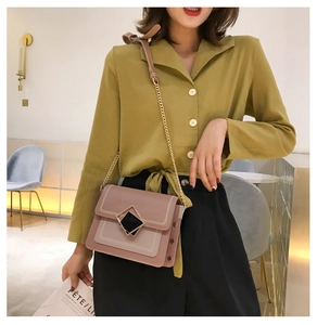 Détail du sac bandoulière rose avec chaîne dorée et boucle géométrique élégante