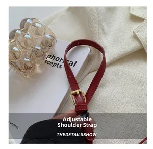 Close-up of a red adjustable leather shoulder strap with a gold metal buckle