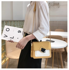 Détail d'un sac bandoulière jaune et blanc chic avec boucle géométrique sur un mannequin
