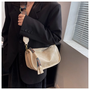Détail de la bandoulière ethnique large et du pendentif bohème sur un sac beige clair