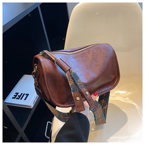Détail du sac cylindrique en cuir marron avec bandoulière large à motifs géométriques