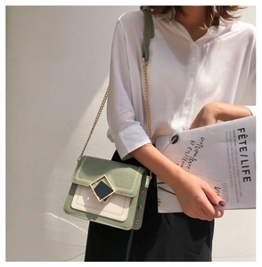 Détail d'un sac bandoulière vert et beige avec boucle dorée et bandoulière chaîne