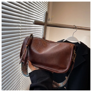 Détail du sac bandoulière vintage marron avec large bandoulière aux motifs ethniques