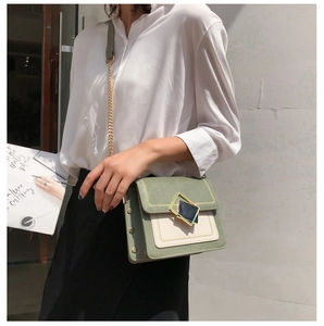 Détail du sac à bandoulière en cuir vert et beige avec boucle et chaîne dorée