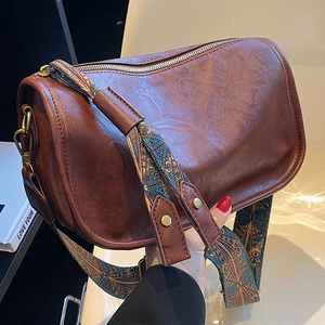 Détail d'un sac bandoulière rétro marron foncé avec large bandoulière ethnique tissée