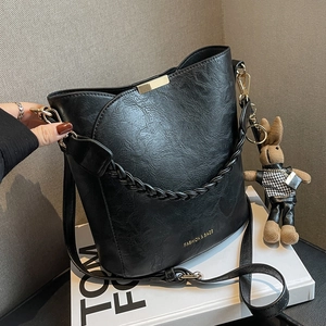 Sac seau vintage noir texturé avec détails dorés et breloque lapin sur socle livre