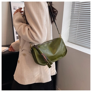 Détail d'un sac bandoulière en cuir vert foncé avec large sangle à motif ethnique
