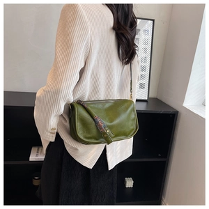 Détail du sac bandoulière vert en similicuir avec sangle à motif porté avec un blazer