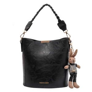 Sac seau vintage noir avec poignée tressée et pendentif lapin décoratif sur fond blanc