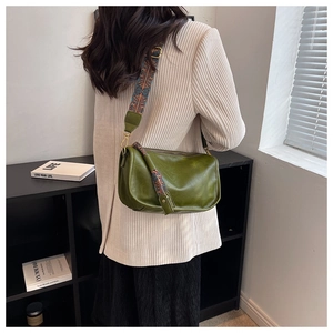 Gros plan du sac bandoulière rétro en cuir vert avec une large sangle tissée géométrique