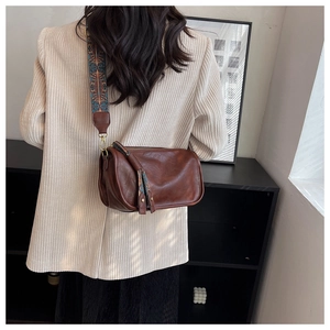 Détail du sac bandoulière en cuir marron foncé avec sangle ethnique et pompon en cuir
