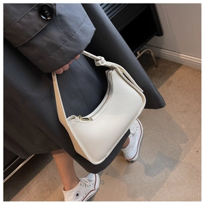 Details der cremeweißen mondförmigen Umhängetasche mit feiner Textur und goldenem Zipper
